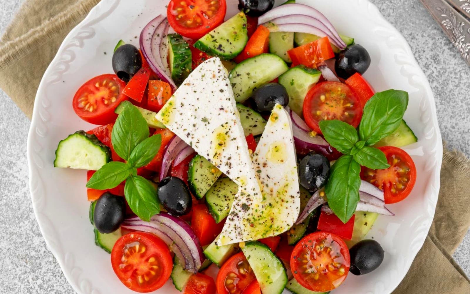 Fresh Greek salad with feta, cucumber, olives, tomato, and basil