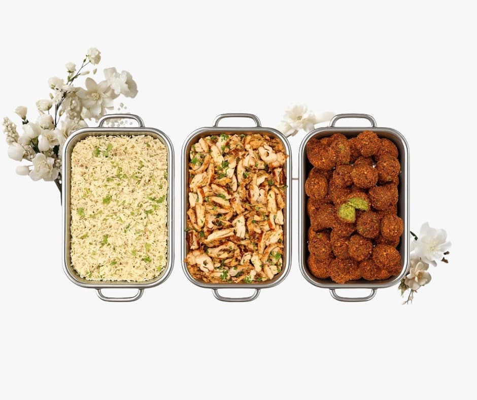 Catering trays with rice, grilled chicken, and falafel